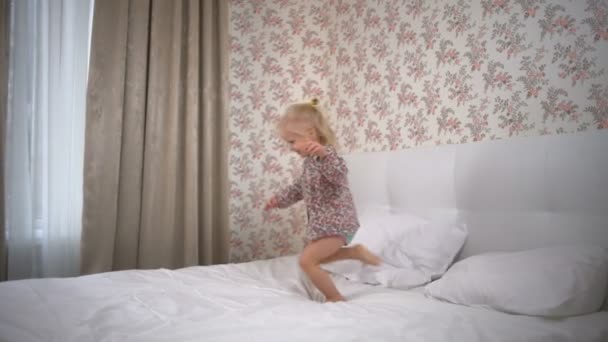 Adorable girl running in circles on the bed and smiling slow motion — Stock Video