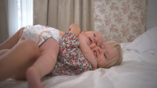 Twee schattige kleine meisjes knuffelen op bed en kijken naar hetzelfde punt Slowmotion — Stockvideo