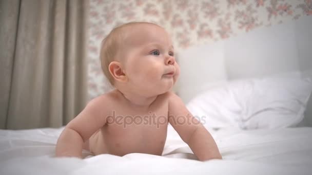 Nice little girl rests on hands on the white bed slow motion — Stock Video