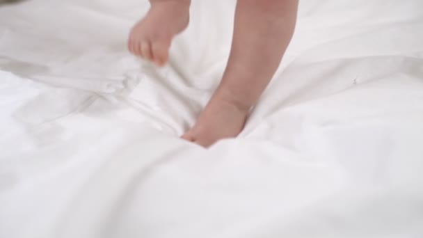 Linda niña tratando de caminar en la cama cámara lenta — Vídeo de stock