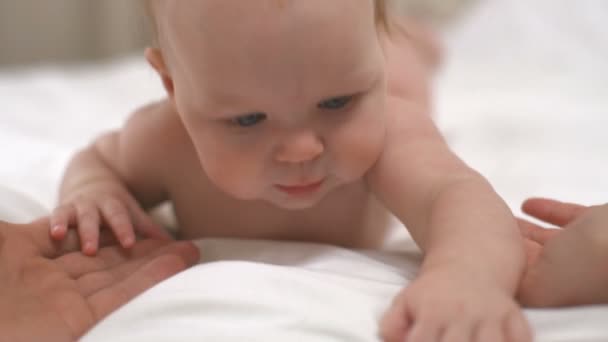 可爱女孩躺在她的肚子上，抱着她的父母手慢动作 — 图库视频影像