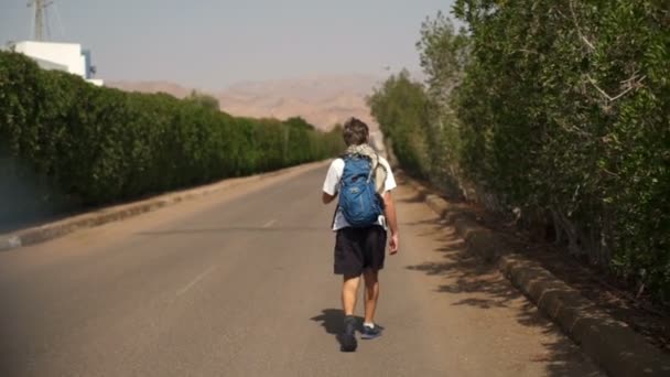 Jeune homme marchant sur la route avec sac à dos au ralenti — Video