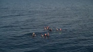 Onların arkadaşı deniz kenarı için ellerini sallayarak dalgıçlar yavaş hareket