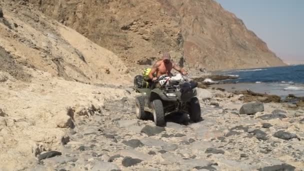 Hombre tatuado en una gorra conduciendo su quad bike cámara lenta — Vídeo de stock