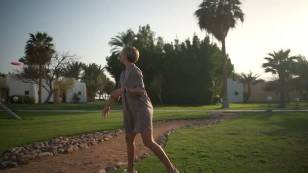 Hermosa mujer en un traje gris lanzando un frisbee cámara lenta — Vídeos de Stock