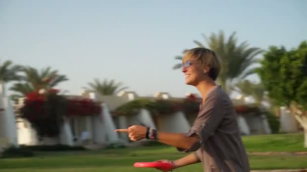 Joven mujer rubia riendo y lanzando un frisbee cámara lenta — Vídeos de Stock