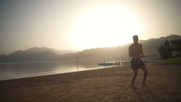 Man in een zwembroek uitgevoerd en een slowmotion frisbee gooien — Stockvideo