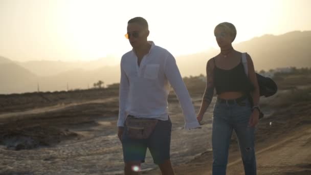 Attractive young couple walking along the road holding hands slow motion — Stock Video