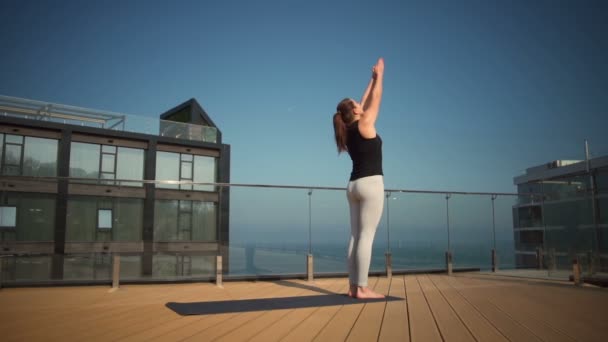 Young attractive female doing yoga on the roof at sea slow motion — Stock Video