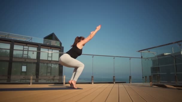 Joven atractiva hembra haciendo yoga en el techo en el mar cámara lenta — Vídeo de stock