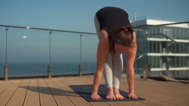 Jeune femme attrayante faisant du yoga sur le toit en mer au ralenti — Video