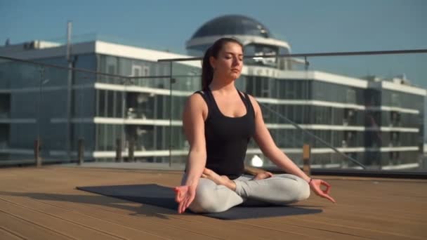 Ung attraktiv kvinna gör meditation på taket vid havet slowmotion — Stockvideo