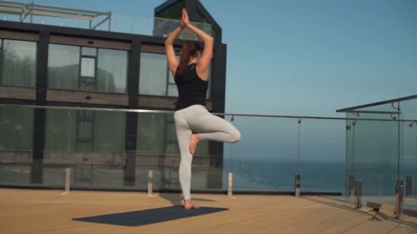 Joven atractiva hembra haciendo yoga en el techo en el mar cámara lenta — Vídeos de Stock