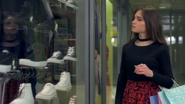 Mujer atractiva joven caminando y la elección de zapatos en la tienda de cámara lenta — Vídeo de stock