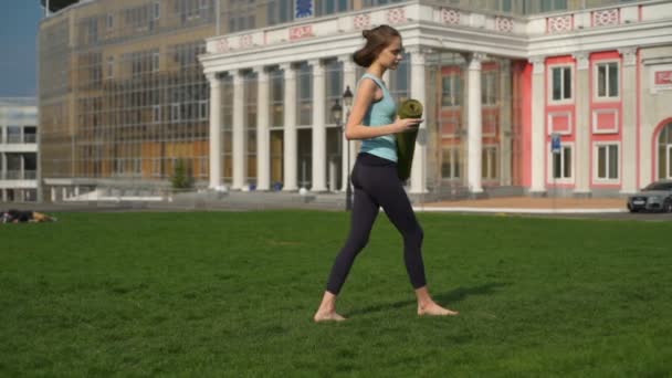 Mladá štíhlá žena připravuje její podložka na cvičení, v parku zpomalené — Stock video