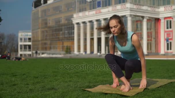 Young slim female sits on mat in lotus pose slow motion — Stock Video