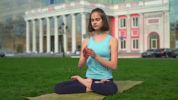Молодая стройная женщина сидит на коврике и делает намасте замедленным движением — стоковое видео
