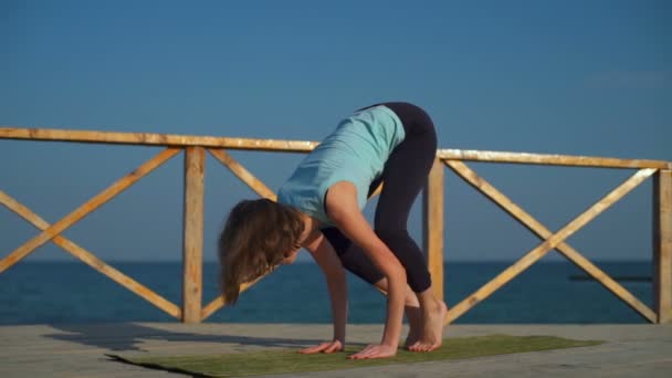 Joven hembra delgada haciendo postura de grúa de yoga cerca del mar cámara lenta — Vídeos de Stock