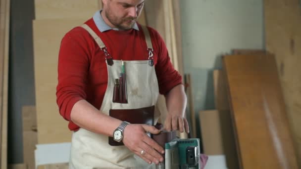 Carpinteiro prepara uma máquina de polimento e liga-a em uma oficina em câmera lenta — Vídeo de Stock