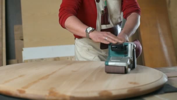 Carpenter slowly moving a polishing machine along the round table in a workshop — Stock Video