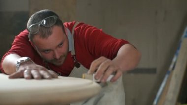 Marangoz dikkatle bir kenar tablo atölye aşındırıcı bir blok ile parlatır