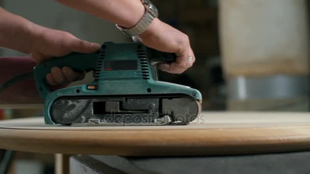 Carpintero puliendo una mesa de madera con una lijadora eléctrica en primer plano del taller — Vídeo de stock