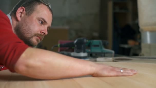 Плотник проверяет результаты своей работы рукой в мастерской — стоковое видео