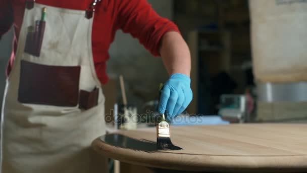 Timmerman in de tabel met een zwarte kleurstof in de workshop schilderen handschoenen — Stockvideo