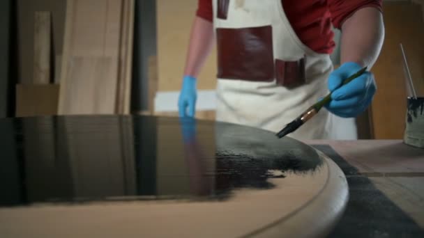 Плотник точно раскрашивает края деревянного стола в мастерской — стоковое видео