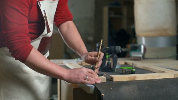 Carpinteiro fazendo marca em um pedaço de madeira com um lápis em uma oficina câmera lenta — Vídeo de Stock