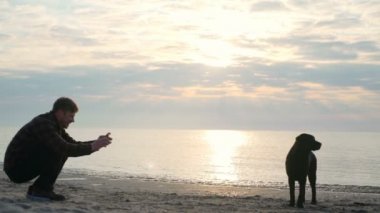 Genç erkek deniz yavaş hareket fotoğraf veya video onun sevimli köpek alır