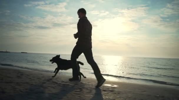 Ung manlig kör med sin hund på havet slow motion — Stockvideo