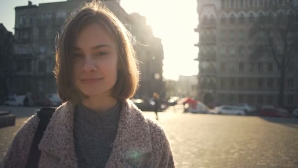 Vonzó fiatal nő néz a kamerába, mosolyog az utcán lassú mozgás — Stock videók