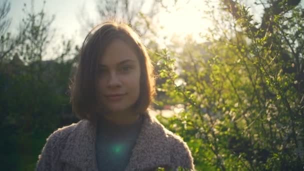 Hermosa mujer mirando a la cámara y sonriendo en el parque de cámara lenta — Vídeos de Stock