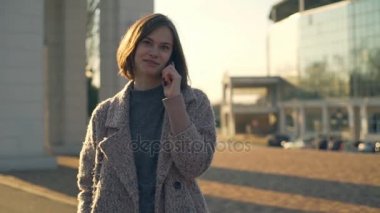 Genç kadın sokak ağır çekim üzerinde gülümseyen telefonda söz