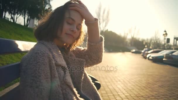 Belle fille assise sur le banc et regardant la caméra au ralenti — Video