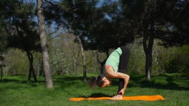 Genç güzel kadın park ağır çekimde sarı halı üzerinde yoga yapar