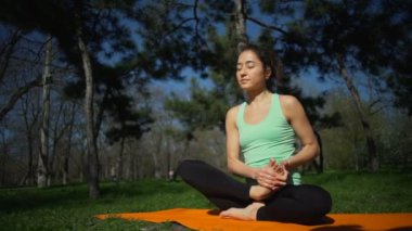 Lotus poz oturan ve halı yavaş hareket üzerinde gülümseyen kadın genç yerleştirmek