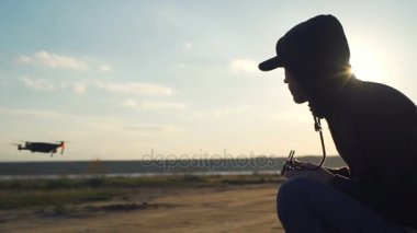 Uzaktan kumanda ile genç erkek oturma ve drone uçuş için arıyorsunuz