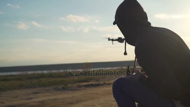 Giovane maschio seduto con telecomando vicino al drone volante colpo da vicino — Video Stock