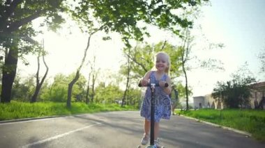 Sevimli küçük sarışın kız onu park ağır çekimde yolda sürme