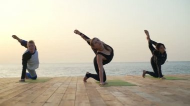 Üç arkadaş yapar yoga egzersiz ahşap iskele ağır çekim