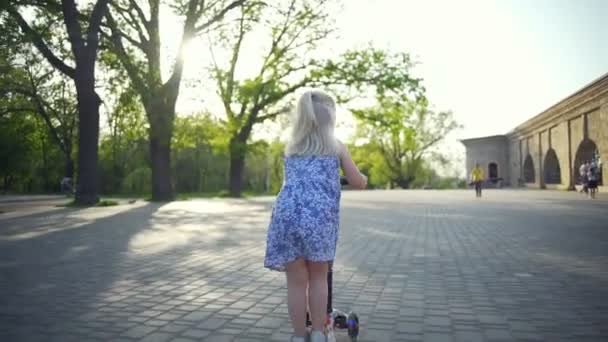 Beautiful blonde girl riding the scooter in the ppark slow motion — Stock Video