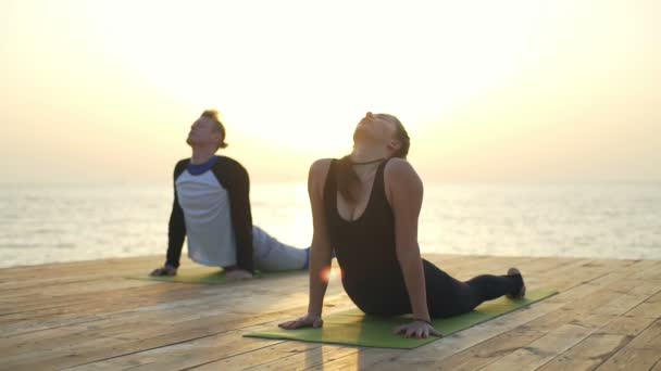 Két személy jóga gyakorlása növelése a saját kezét lassú mozgás — Stock videók