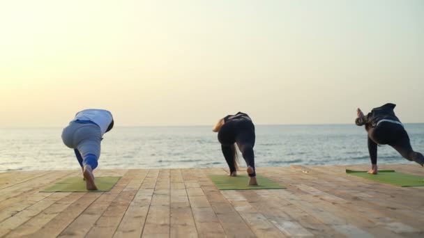 Vänner gör yogaövningar på träpiren i morgon slow motion — Stockvideo