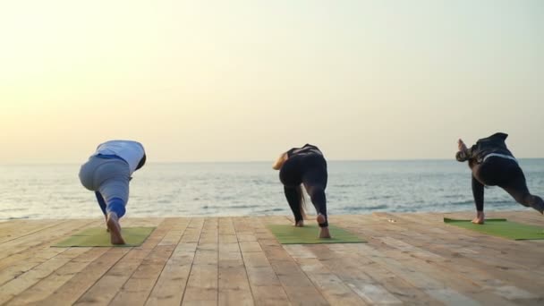 Arkadaşlar sabah yavaş çekimde ahşap iskele üzerinde yoga egzersizleri yapıyor — Stok video