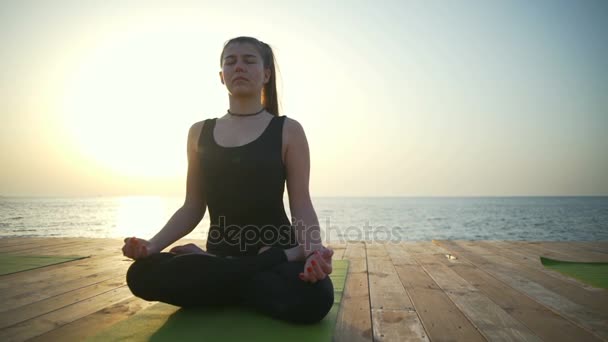 Mooie vrouw zitten in de lotus-pose op het houten terras slow motion — Stockvideo