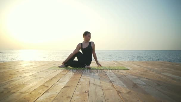 Красивая женщина делает упражнения йоги на деревянном пирсе замедленной съемки — стоковое видео