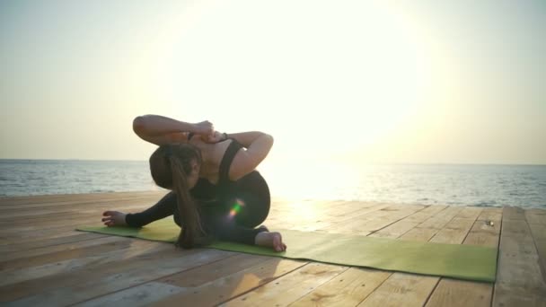 Kobieta siedzi w jogi, rozciągający się w pobliżu morza zwolnionym tempie — Wideo stockowe