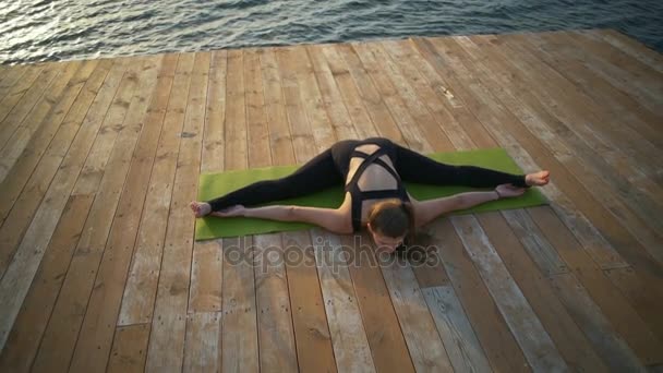 Beautiful flexible woman sits on the twine near the sea slow motion — Stock Video